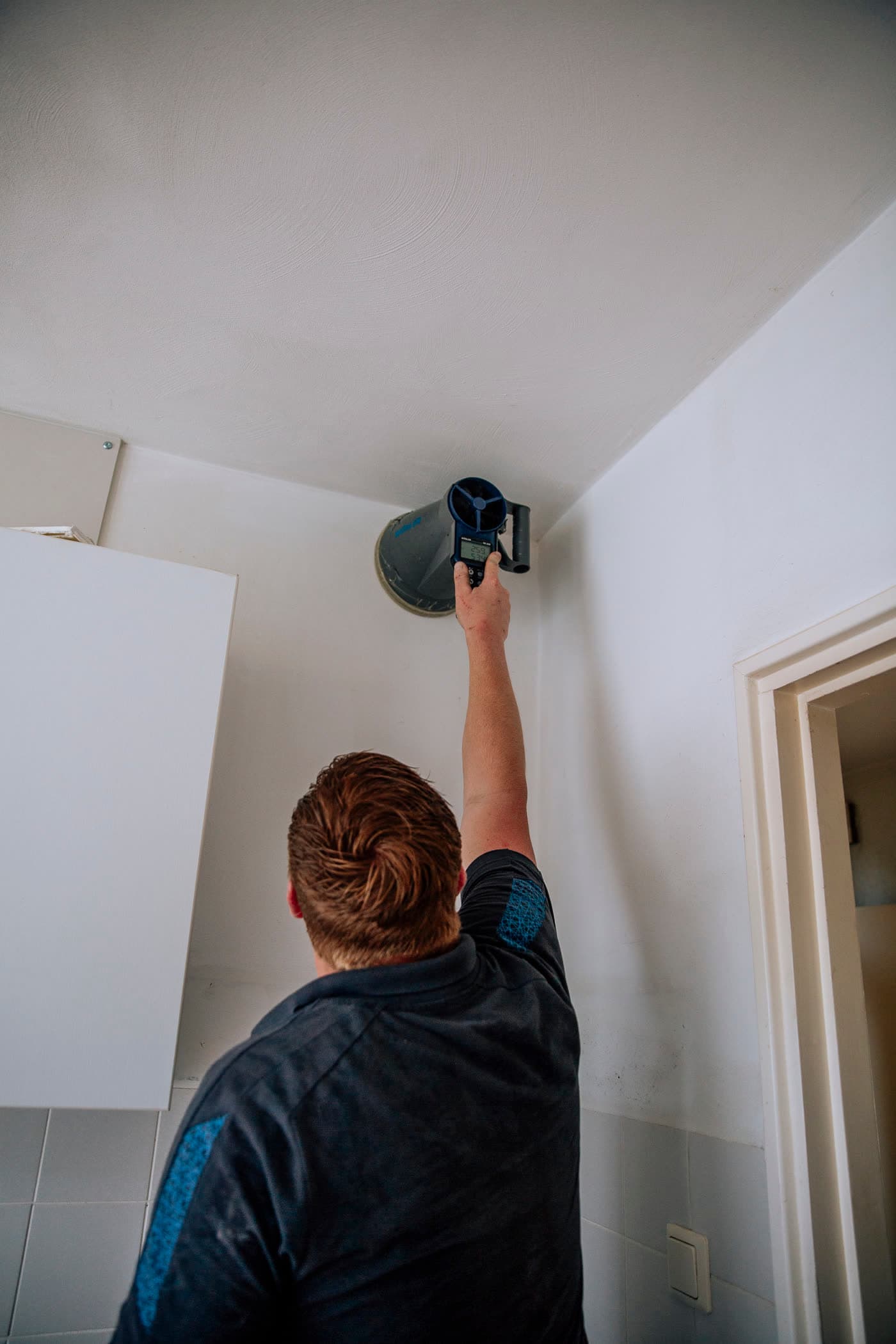 Monteur meet de luchtstroom bij een ventilatieventiel